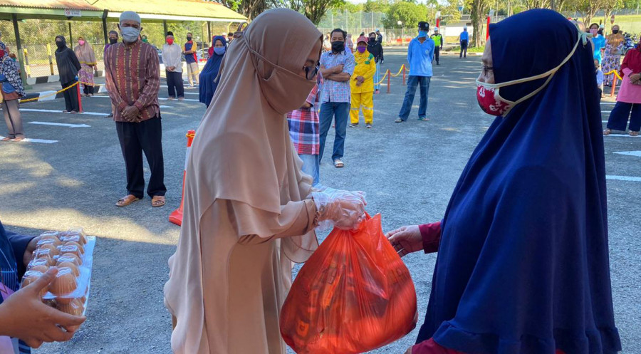 Ketua Bidang Sosial Budaya PWP Tingkat Pusat PT Badak NGL, Puji Fany, saat memberikan sembako kepada salah satu warga yang berhak menerima bantuan dari PWP, Senin (11/5/2020), di halaman Pos Security Badak NGL, Kampung Baru, Bontang Selatan.