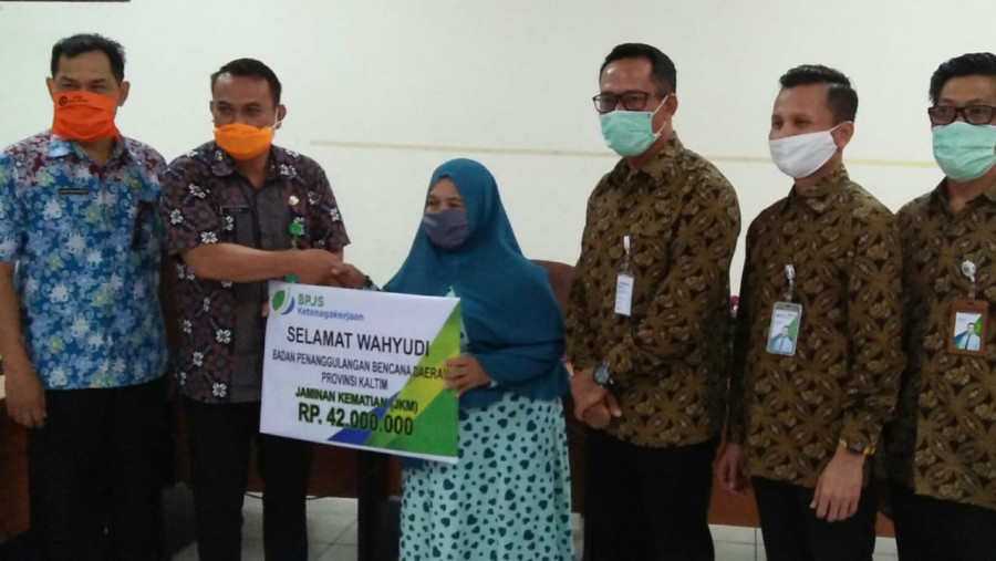Ibu Sahrijat (ketiga dari kiri) secara simbolis menerima santunan Jaminan Kematian dari BPJS Ketenagakerjaan yang diserahkan Kasubag Umum BPBD Kaltim, Yasir (kedua dari kiri). (Foto: Maruly)