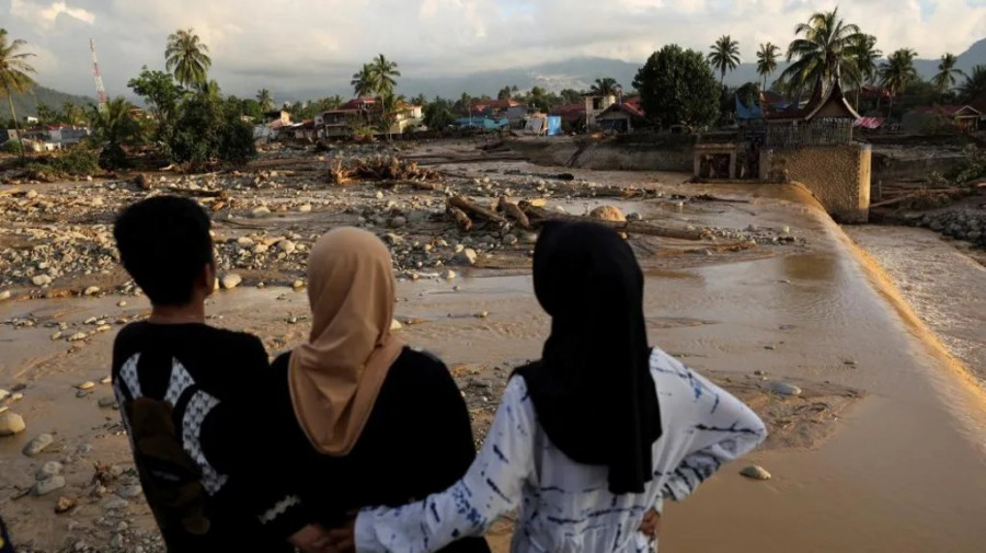 Warga saat melihat kerusakan akibat banjir di Padang. (reuters)