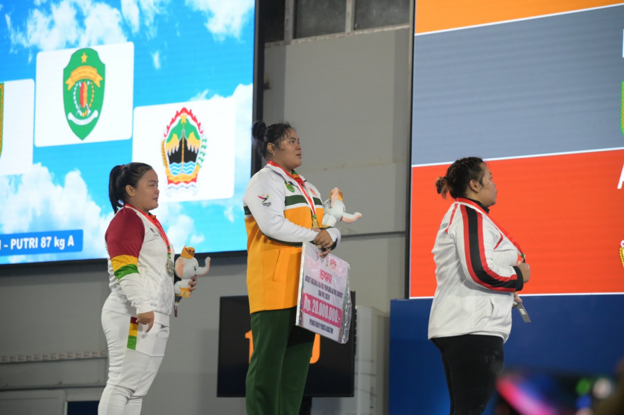 Firda (tengah) berdiri diatas podium pertama usai dikalungkan medali. (Foto: Dok.Angkat Besi)
