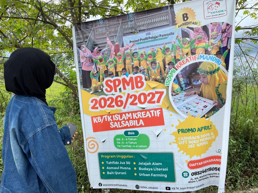 Warga di kawasan Kelurahan Lempake mengamati papan pengumuman terkait Seleksi Penerimaan Murid Baru (SPMB) tahun ajaran 2026/2027. (Ayu/KoranKaltim.com)